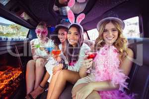 Frivolous women drinking cocktails in a limousine