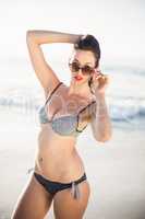 Portrait of glamorous woman in bikini and sunglasses standing on
