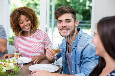 Young man drinking wine with friends at home