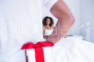 Man hiding gift behind his back for wife