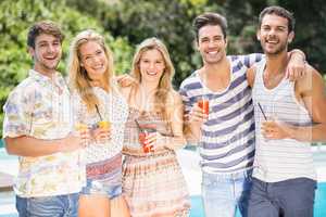 Portrait of friends having juice near pool