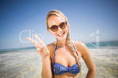 Happy woman showing victory sign on the beach