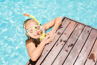 Happy woman with snorkel gear leaning on pool side