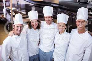 Happy chefs team standing together in commercial kitchen