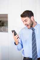 Businessman shouting while looking in mobile phone