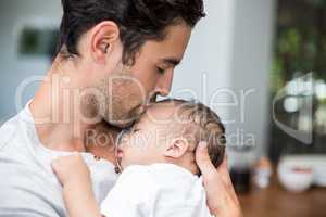 Close-up of father kissing baby while standing