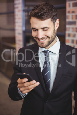 Happy businessman using cellphone in office