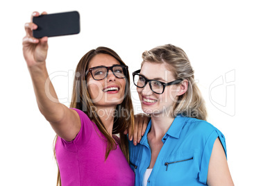 Smiling female friends taking self portrait with smartphone