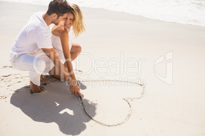 Couple drawing heart on sand