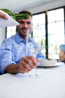 Waiter pouring wine in a glass of costumer