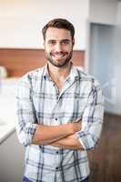 Confident man with arms crossed by kitchen counter