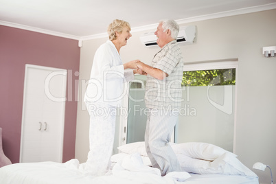 Cheerful senior couple jumping on bed