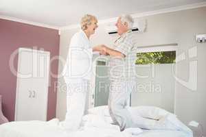 Cheerful senior couple jumping on bed