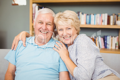 Senior couple sitting on sofa against bookshelf