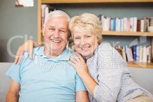 Senior couple sitting on sofa against bookshelf
