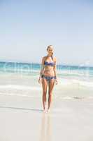 Happy woman in bikini standing on the beach