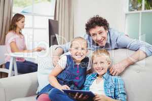 Happy children with father by sofa at home
