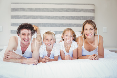 Portrait of happy family resting on bed