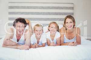 Portrait of happy family resting on bed