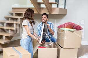 Smiling couple unpacking computer from cardboard box