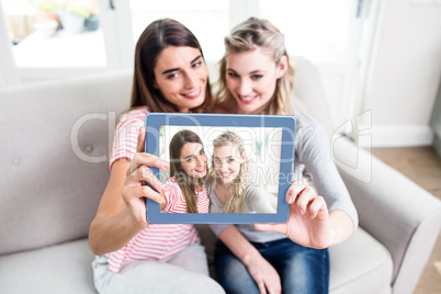 Young female friends taking selfei at home