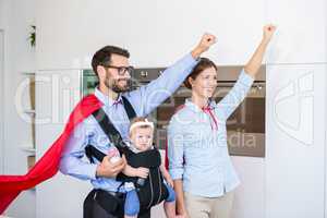 Couple in superhero costume carrying daughter