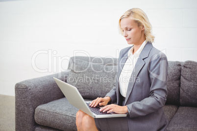 Bussinesswoman working on laptop while sitting on sofa