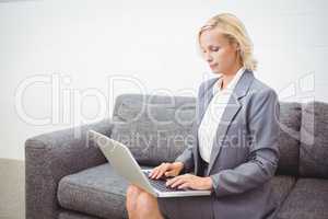 Bussinesswoman working on laptop while sitting on sofa