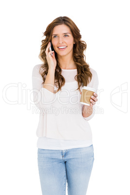 Happy young woman talking on mobile phone while having coffee