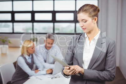 Businesswoman using digital tablet while colleague in background