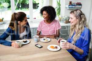 Female friends laughing while having breakfast