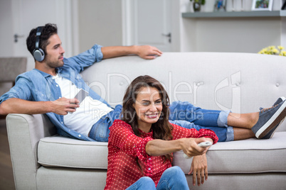 Man listening to music while woman changing channel