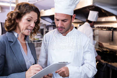 Female restaurant manager writing on clipboard while interacting