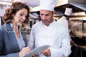 Female restaurant manager writing on clipboard while interacting