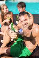 Young man having beer at the swimming pool