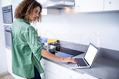 Woman working on laptop while cooking