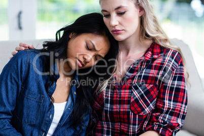 Woman consoling depressed female friend at home