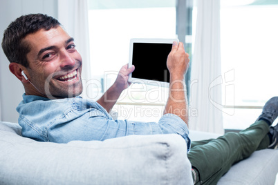 Portrait of young man listening to music while using tablet