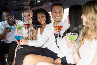 Well dressed people drinking cocktails in a limousine