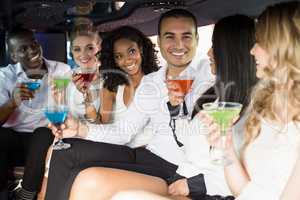 Well dressed people drinking cocktails in a limousine