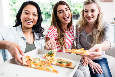 Beautiful happy female friends eating pizza