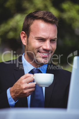 Businessman using laptop having a coffee