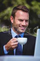 Businessman using laptop having a coffee