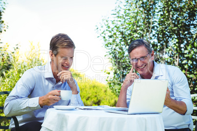 Casual businessman looking at laptop and having coffee