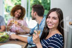 Happy young woman drinking wine with friends