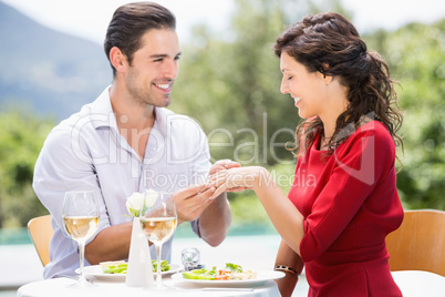 Smiling man wearing engagement ring to woman