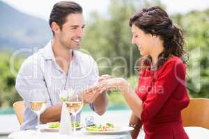 Smiling man wearing engagement ring to woman