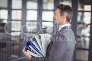 Businessman carrying files stack in office