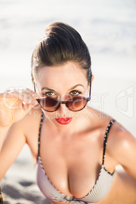 Glamorous woman in bikini looking over sunglasses