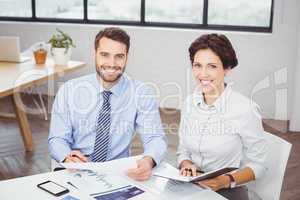 Happy business people with documents sitting in office